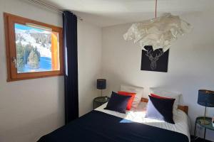 1 dormitorio con 1 cama con almohadas azules y rojas en Joli T2 Superdévoluy 4 pers !, en Superdevoluy