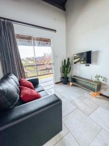 a living room with a couch and a large window at Namaste Flats Praia do Rosa in Imbituba