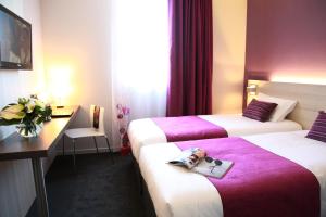 a hotel room with two beds with a magazine on them at Brit Hotel Vannes - Theix Golfe du Morbihan in Theix +27 photos