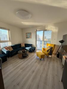 a living room with a blue couch and yellow chairs at Apartament Relax in Gdańsk