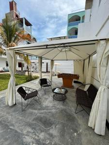 a patio with chairs and an umbrella in front of a building at La Arteza Pacasmayo in Pacasmayo