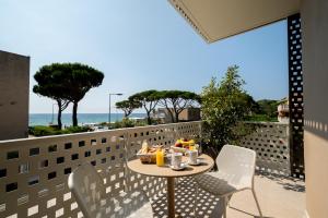 a table and chairs on a balcony with a view of the ocean at Hôtel La Ménado in Cavalaire-sur-Mer
