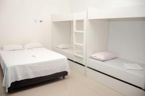 a bedroom with two bunk beds with white walls at Sua Casa em Maresias I in São Sebastião