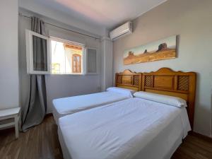 two beds in a small bedroom with a window at Pensión Duquesa Bed & Breakfast in Granada