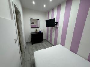 a room with a bed and a tv on a striped wall at Meghan Home in Catania