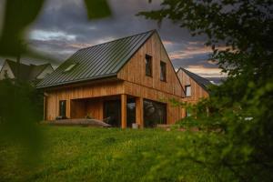 a wooden house with a metal roof on a field at Chaty Jagi Domek 2 in Czorsztyn