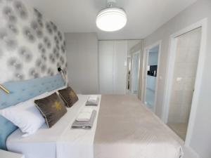 a bedroom with a large white bed with a blue headboard at Gandia Playa Apartament Claudia Lux con vistas al mar in Playa de Gandia