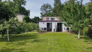 a white house with a yard with trees at Domki na Wodnej in Kołobrzeg