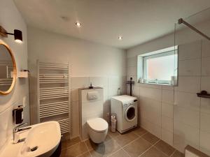 a bathroom with a toilet sink and a washing machine at M&N Apartments in Bad Bevensen