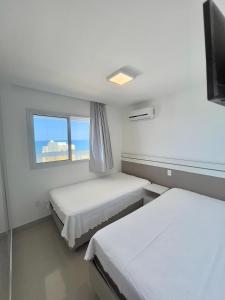 Giường trong phòng chung tại VISTA MAR DESLUMBRANTE, apto novo e moderno, a uma quadra da praia, redes de proteção, quartos com ar condicionado, roupas de cama e banho, TV 65, wi fi, Sky, cadeiras de praia, prédio com piscina, portaria 24 horas e 2 vagas