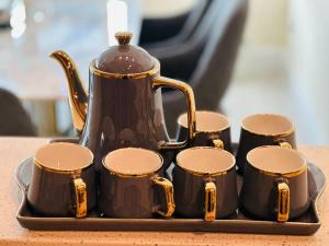 a tea pot and four cups on a tray at Centaurus Apartment in Islamabad