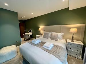 a bedroom with a large white bed with a green wall at The Card Room at Ryedale House in York