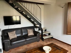 un soggiorno con divano in pelle nera e scala di House in Tuscany - Casa La Scala a Gaiole in Chianti