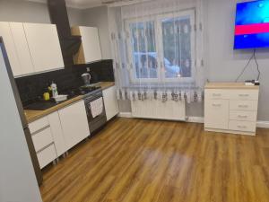 a kitchen with white cabinets and a wooden floor at Apartament mieszkanie do wynajęcia Nicola in Wałbrzych