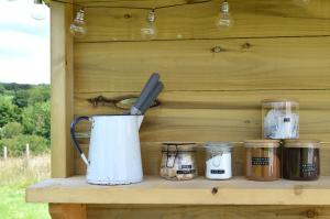 a wooden shelf with a tea pot and jars at Mallard - 5m Luxury Bell Tent at Tregonetha Lake - Tylda Tents in Saint Columb Major