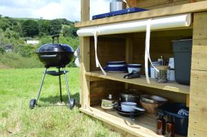 a grill on a stand in a wooden shed at Mallard - 5m Luxury Bell Tent at Tregonetha Lake - Tylda Tents in Saint Columb Major