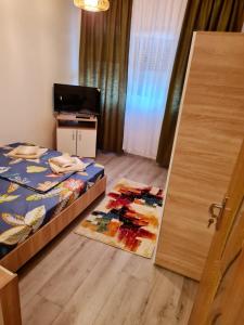 a bedroom with a bed and a door with a rug at Apartament Costescu 2 in Băile Herculane