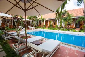 a pool with two lounge chairs and an umbrella at Little Garden Bungalow in Phu Quoc