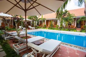 a pool with two lounge chairs and an umbrella at Little Garden Bungalow in Phú Quốc