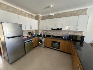 a kitchen with white cabinets and a stainless steel refrigerator at Gaia Luxury chalet in Dawwār Abū Maḩrūs