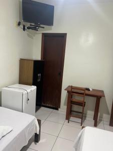 a room with a refrigerator and a table and a television at Hotel Brilhante 2 in Itacarambi