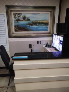 瓜拉派瑞Apartamento Guarapari Castanheiras的一张桌子,上面有一台电脑和一张墙上的照片