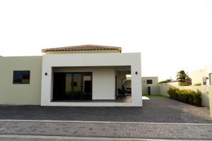 a white house with a patio in a driveway at Elisabeth Residence Mambo Beach in Dominguito