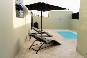 a pair of chairs and an umbrella next to a swimming pool at Elisabeth Residence Mambo Beach in Dominguito