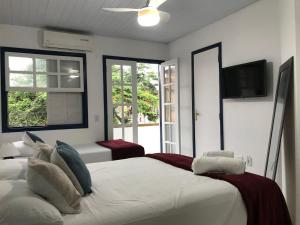 a bedroom with a large white bed and windows at Brothers Suites Centro Búzios in Búzios