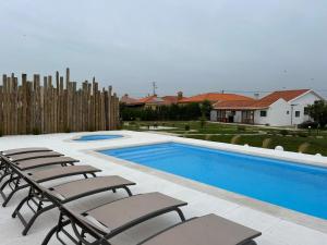 a swimming pool with lounge chairs next to a house at Villa Ria by Aqualeisure in Ovar