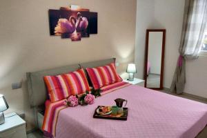 杜比诺Tra lago e montagne home nonna Maria的一间卧室配有一张粉红色的床,上面有盘子的食物