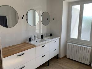 a white bathroom with a sink and two mirrors at La Maison de Marie in Biollet +38 photos