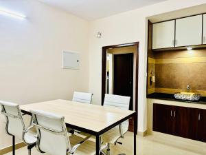 a dining room with a table and white chairs at AL-KABEER SERENE POND RETREAT KOWDIAR 4bhk in Trivandrum +29 photos