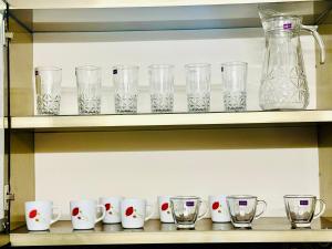 a row of cups and glasses on a shelf at AL-KABEER SERENE POND RETREAT KOWDIAR 4bhk in Trivandrum