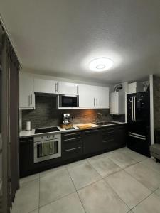 ヴェニシューにあるAppartement t3 70 m2のキッチン(白いキャビネット、黒の電化製品付)