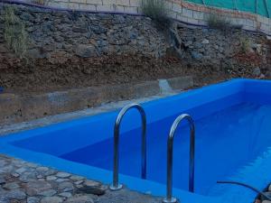 a blue swimming pool next to a stone wall at Cortijo Rural Al-Andalus con Piscina in Órgiva