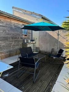 two chairs and a table with an umbrella on a deck at De bric et de broc , maison à 100m plage in Asnelles +2 photos