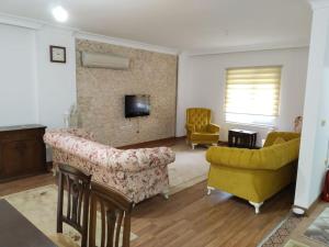 ein Wohnzimmer mit einem gelben Sofa und Stühlen in der Unterkunft Denize Yakın Geniş Villa in Hurmaköy