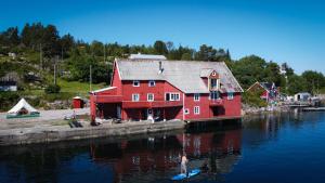 a red house sitting on the water next to a body of water at Drømmebrygga in Averoy