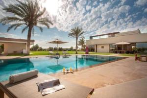 a large swimming pool in front of a house at Villa des stars in Marrakesh