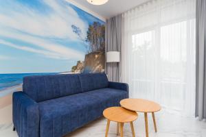 Una sala de estar con un sofá azul y una mesa. en Apartament Baltic Park IIIB z Basenem Letnim by HolidaySun, en Sianożęty