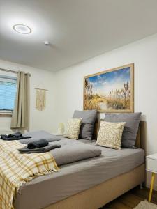 a bedroom with a large bed with a painting on the wall at Charmante Ferienwohnung in Scharbeutz -Ihr perfektes Zuhause am Meer! Terasse, Parken & Strand! W1 in Scharbeutz