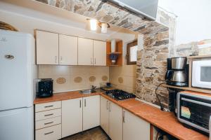 a kitchen with white cabinets and a stone wall at Casa Roland in Sovata