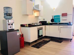 a kitchen with white cabinets and a stove and a refrigerator at Harmony Homes Beachfront in Diani Beach