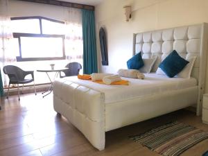 a bedroom with a large white bed with blue pillows at Harmony Homes Beachfront in Diani Beach +22 photos