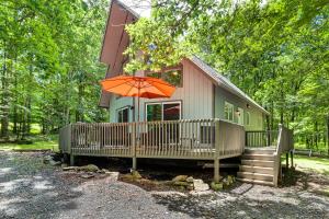 a small house with an orange umbrella in front of it at Furnished Deck and Fire Pit Poconos Outdoorsy Gem in Albrightsville