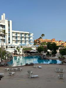 a large swimming pool with lounge chairs in a parking lot at Zen Apartment Tenerife in San Miguel de Abona