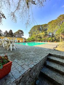 a swimming pool with a table and chairs next to it at Fazenda com fácil acesso - Piscina e churrasqueira in Biritiba-Mirim