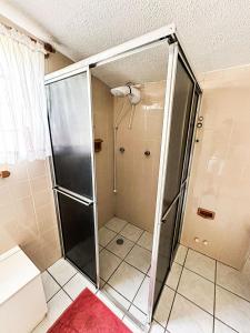 a shower with a glass door in a bathroom at Fazenda com fácil acesso - Piscina e churrasqueira in Biritiba-Mirim