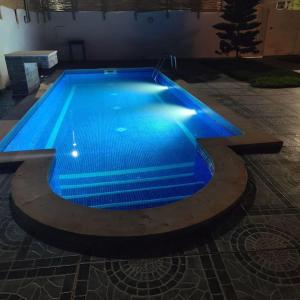 ein großer Pool mit blauer Beleuchtung in einem Gebäude in der Unterkunft Villa au cœur de l'île in Taguermess